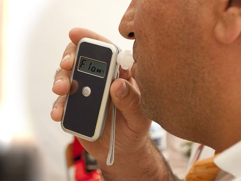 A man blows into a breath test apparatus